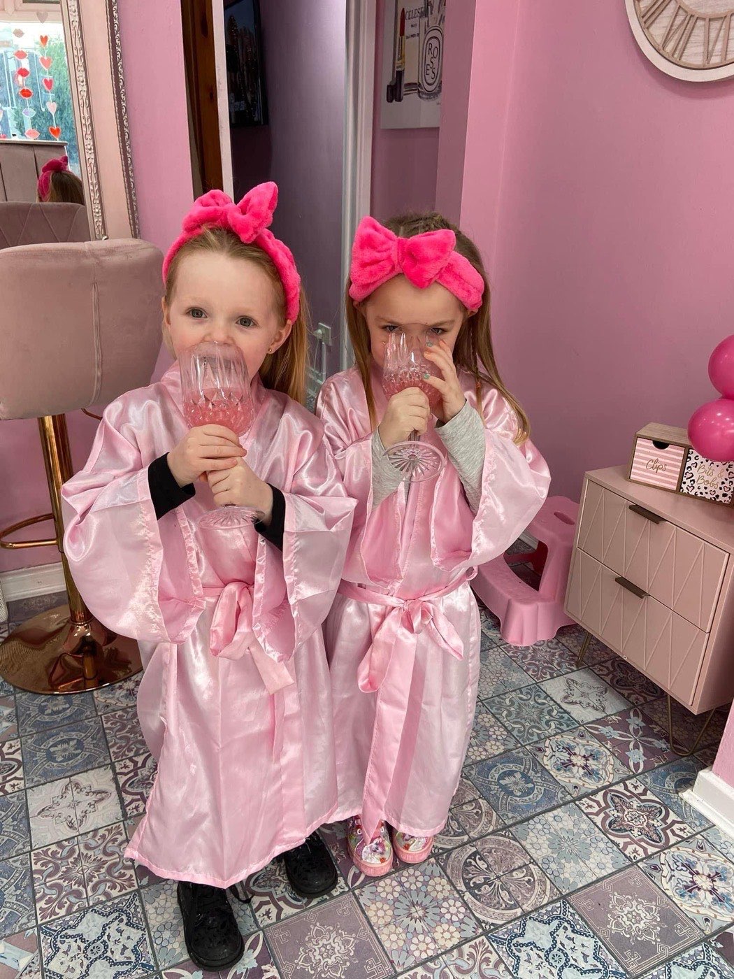 Two children in pink robes and headbands with mocktails at Little Miss Pamper, the children's pamper salon in Winton, Eccles